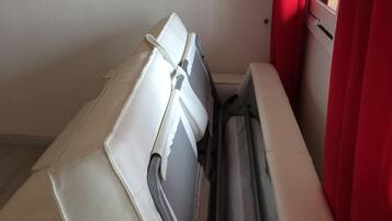 A small, enclosed space with a beige sofa and a window with red curtains.