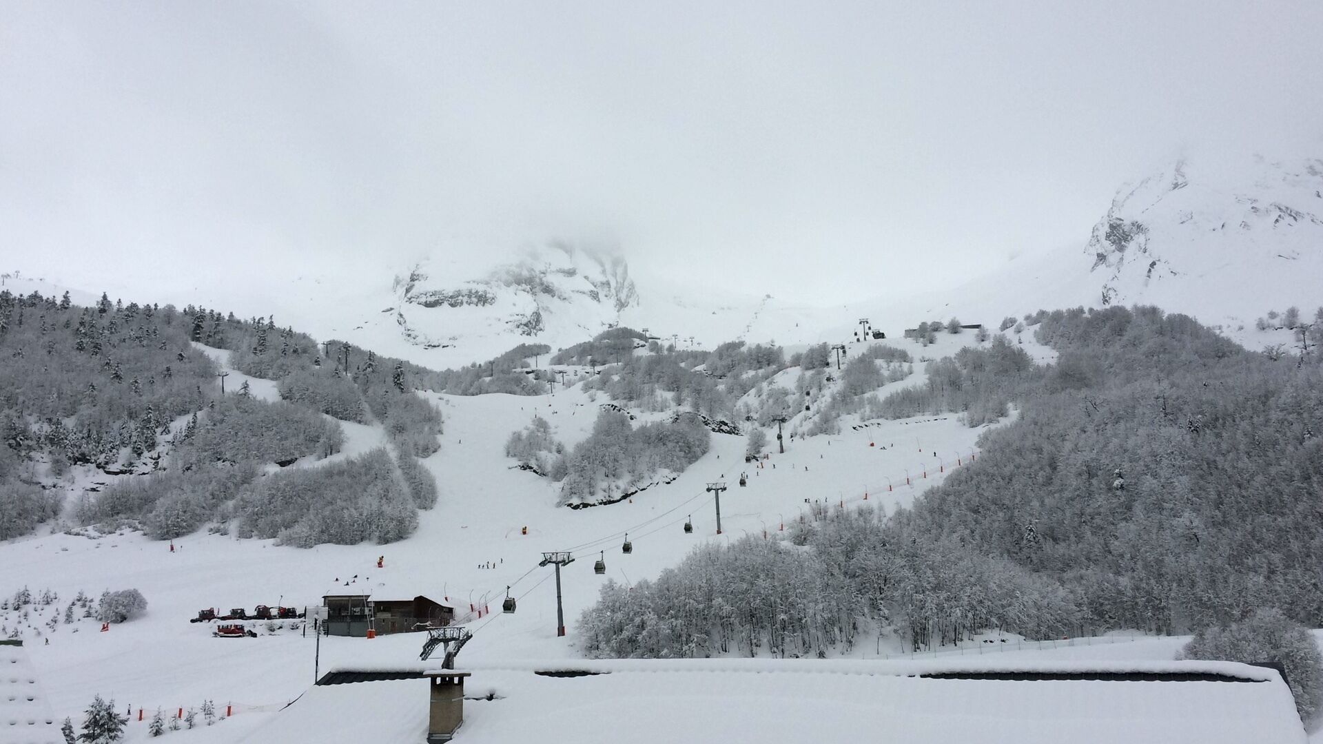 Une station de ski enneigée, dotée de remontées mécaniques, d’un chalet et de pistes bordées de forêts.