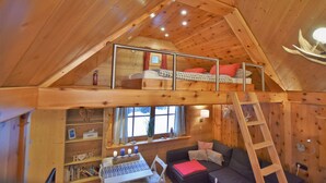 Ein gemütliches Blockhaus mit Schlafzimmer auf dem Dachboden, Essbereich und Wohnzimmer.