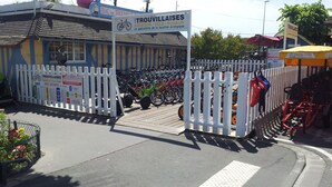 Ein Fahrradverleih namens Trouvillaises mit weißem Zaun und einem Schild.