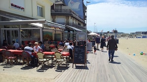 Ein Restaurant direkt am Strand mit Terrassenplätzen, einer Speisekarte und einem hölzernen Steg.