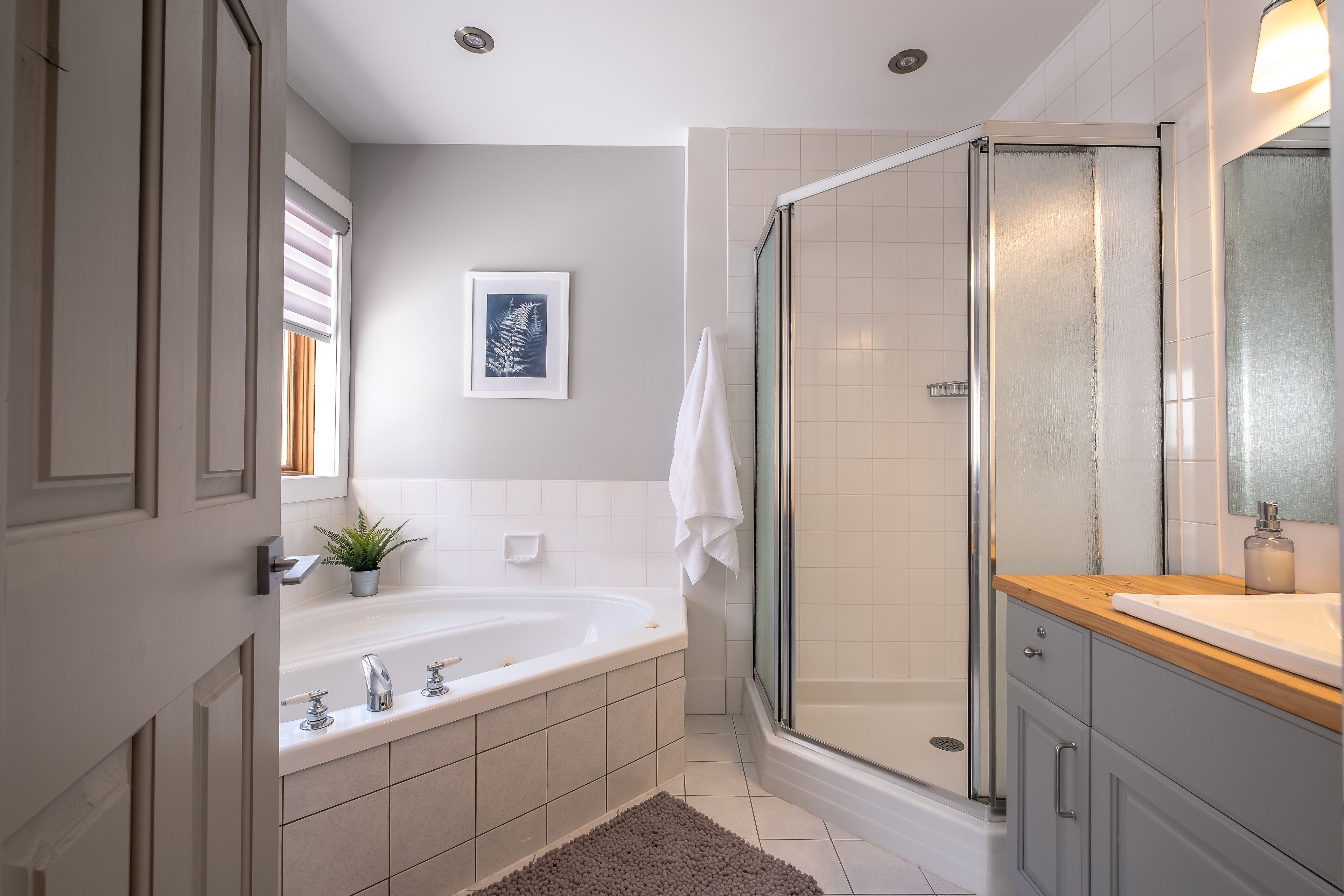 A modern bathroom with a bathtub, shower, and vanity.