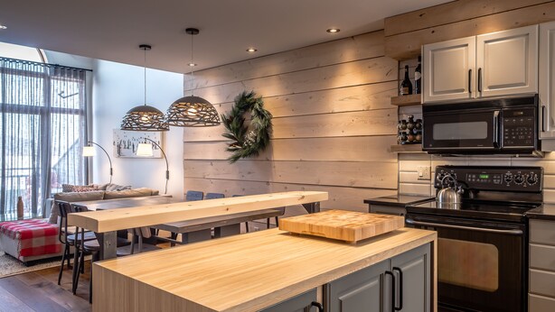 Une cuisine moderne dotée d’un îlot central en bois, d’un four à micro-ondes encastré et d’un four traditionnel.