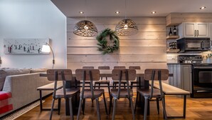Une cuisine moderne avec des murs recouverts de panneaux en bois, un coin repas avec une table et des chaises, et un four à micro-ondes.