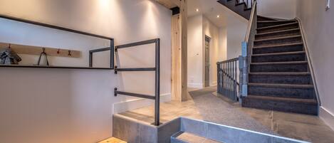 A modern staircase with a wooden handrail and a metal banister, leading to a second floor.