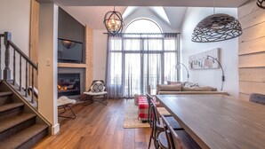 Un vaste espace de vie doté d’un plancher en bois, d’une grande table à manger et d’une cheminée.