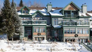 Un grand immeuble à étages, de style architectural traditionnel, qui se distingue par une entrée imposante dotée d’un porche et de nombreuses fenêtres.