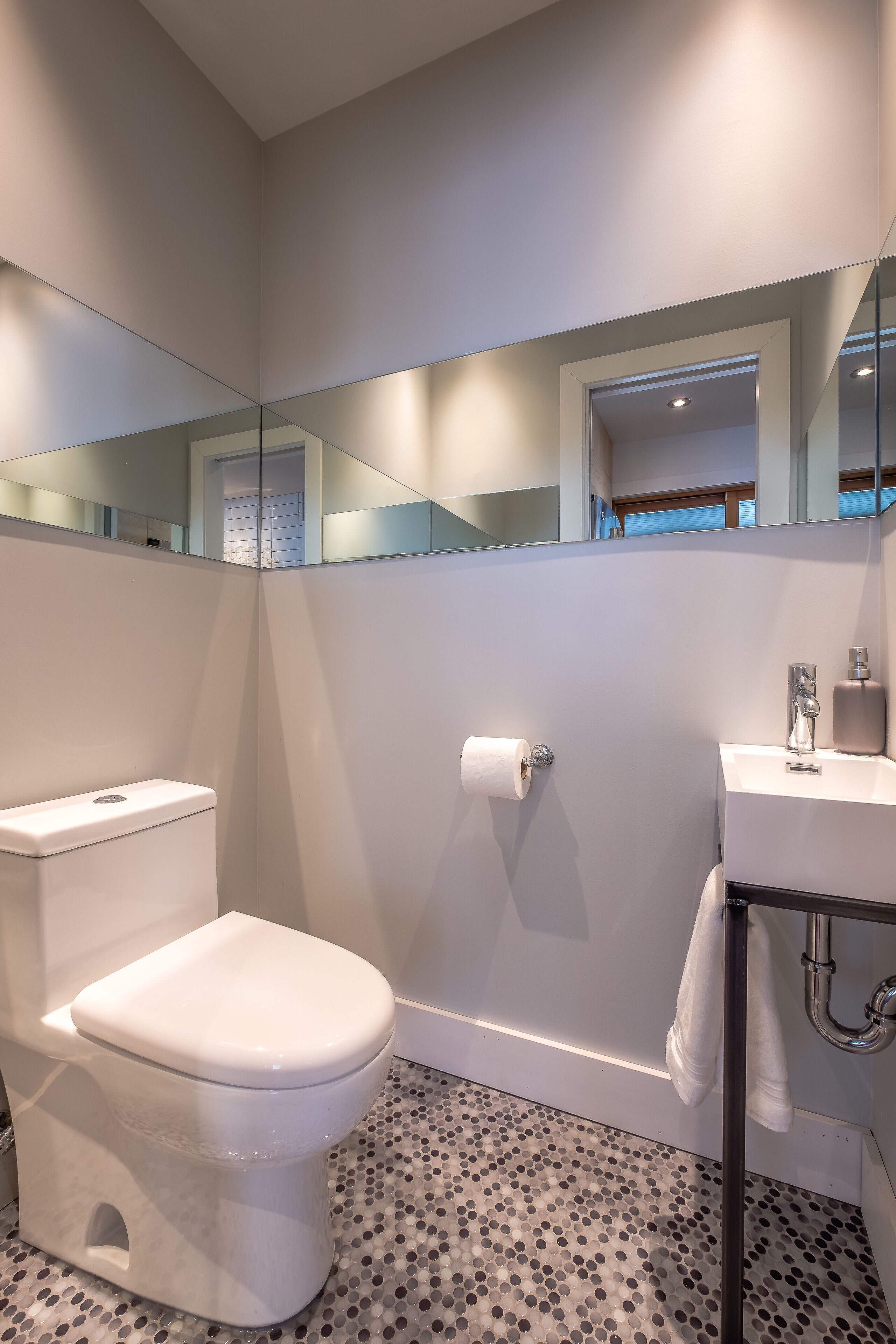 Ein modernes Badezimmer mit Toilette, Waschbecken und Spiegel.