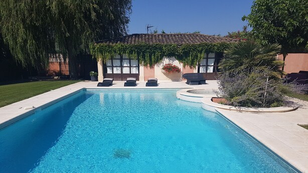 A rectangular swimming pool with clear blue water, surrounded by a tiled deck. - Charming apartment in Provence (Châteaurenard)