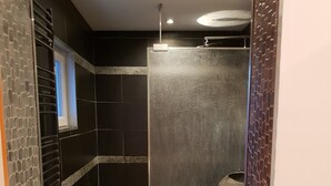 A modern kitchen with black tiles, a stainless steel sink, and a 'WATER' sign. - Charming apartment in Provence (Châteaurenard)