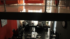 Un salón moderno con techo de cristal, paredes rojas y sofás naranjas.