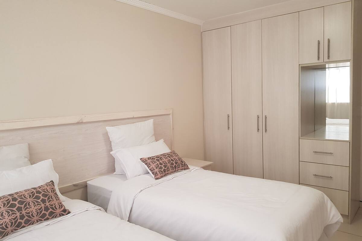 Habitación de hotel con dos camas, un armario y un espejo.