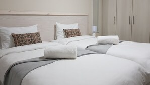 Una habitación de hotel con una cama grande, una mesita de noche, un espejo y un armario.