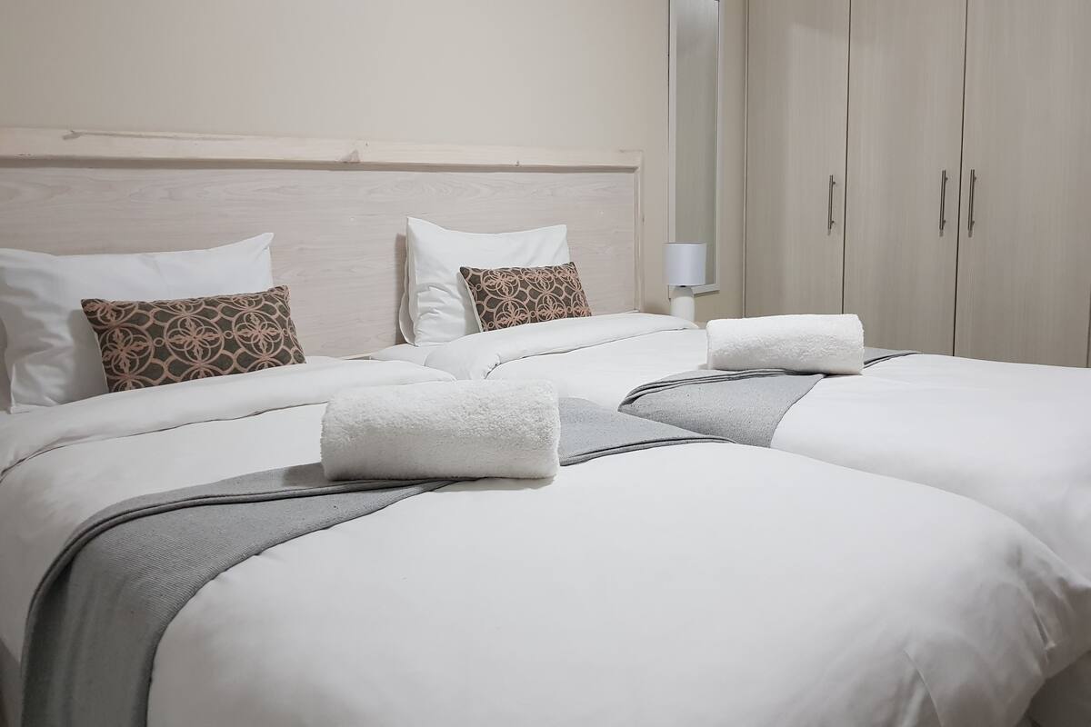 Una habitación de hotel con una cama grande, dos almohadas, una mesita de noche y un armario.