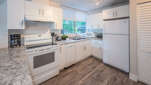 Una cocina moderna con armarios blancos, horno empotrado, microondas y refrigerador.