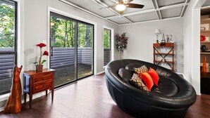 Ein modernes Wohnzimmer mit einem schwarzen Ledersofa, einem Holztisch mit einem Topfpflanzen und einem Deckenventilator.