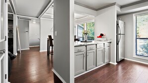 Eine moderne Küche mit grauen Schränken, einem Edelstahl-Kühlschrank und einem Fenster mit Jalousien.