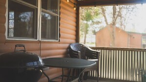 A covered outdoor area with a grill, a table, and two chairs. - 3BR Lakefront Cabin w/ Private Launch & Dock (Backus)