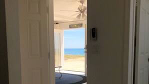 Une chambre d’hôtel avec vue sur la plage et l’océan, accessible par une porte ouverte.