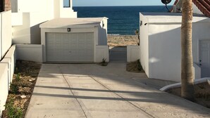 Une propriété située sur la côte, avec un garage blanc, un palmier et une vue sur la mer.