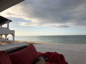 Relax in a serene outdoor seating area with a stunning sea view, featuring a comfortable lounge chair and a cozy blanket.