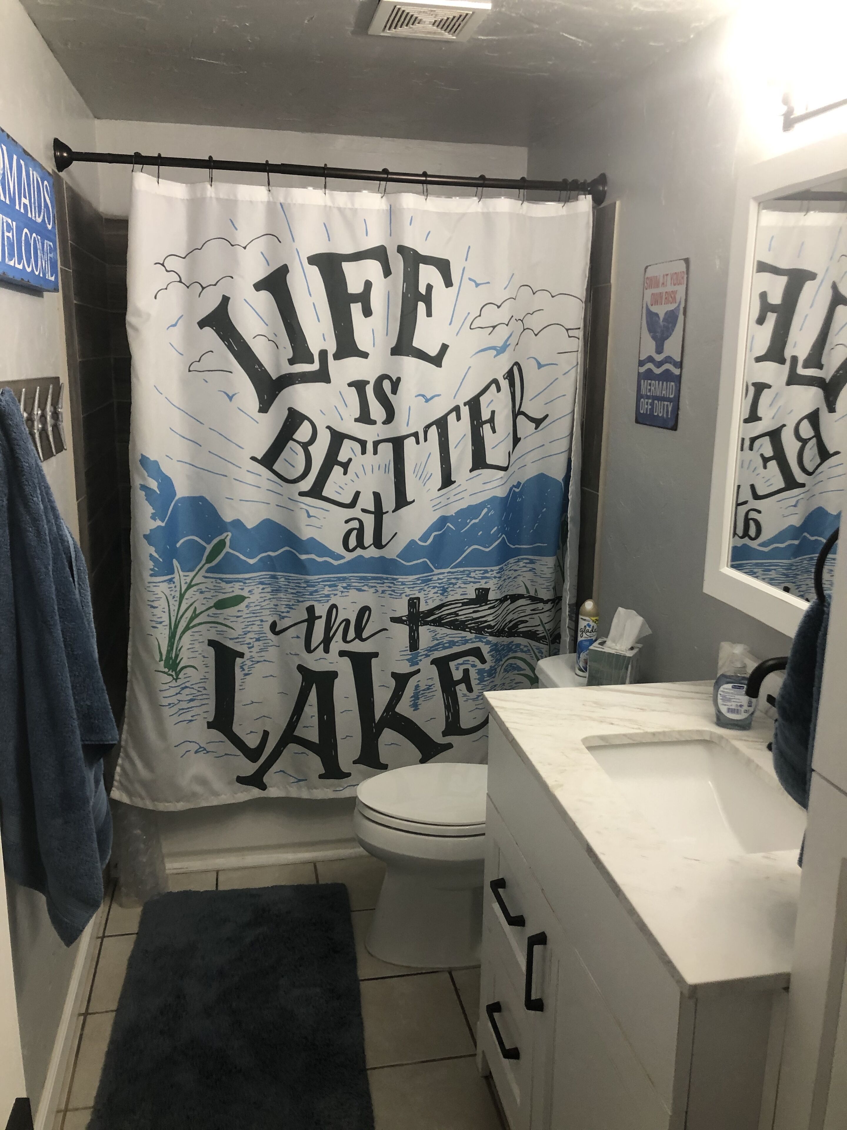 Ein Badezimmer mit Duschvorhang, Toilette, Waschbecken und Spiegel.