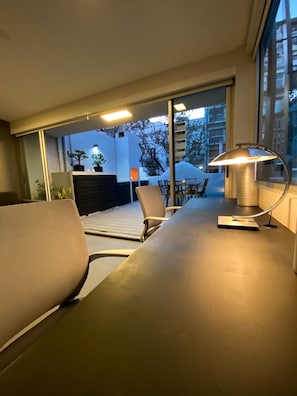 Enjoy a serene view from the room's large window, overlooking the outdoor deck and lush greenery.