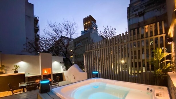 Ein Poolbereich auf dem Dach mit Whirlpool, Sitzgelegenheiten und Blick auf umliegende Gebäude.