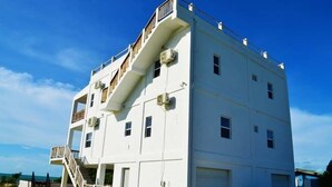 Ein mehrstöckiges Gebäude mit einer Treppe, die zu einem Balkon führt, einer Garage und freiem Blick zum Himmel.