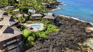 A coastal resort with multiple bungalow-style buildings, a central swimming pool, and a rocky shoreline. - 🏖️Oceanfront Kona Townhome w/ A/C | Walk to Magic Sands (Kailua Kona)