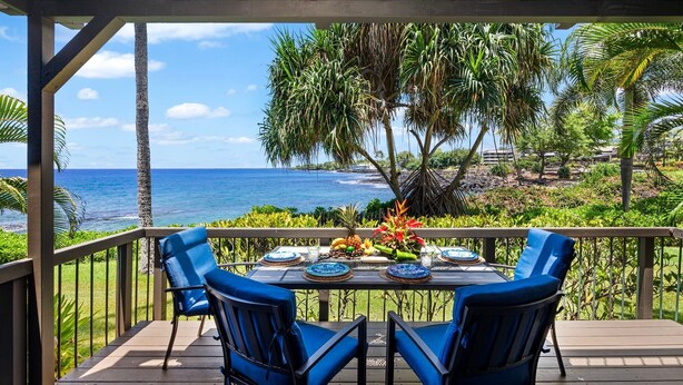 A covered outdoor dining area with a table set for four, overlooking a beach with palm trees and the ocean. - 🏖️Oceanfront Kona Townhome w/ A/C | Walk to Magic Sands (Kailua Kona)