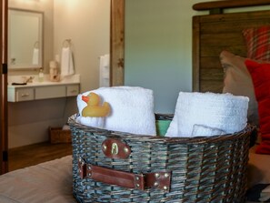 A wicker basket with towels and a rubber duck on a bed.