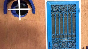 A building facade with a blue door and a circular window with a white cross. - A Great Value Doesn’t Last Long  (Marrakech)