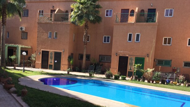 A swimming pool with a tiled deck, surrounded by a well-maintained lawn and potted plants. - A Great Value Doesn’t Last Long  (Marrakech)