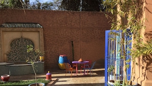 A courtyard with a tiled floor, a seating area with colorful chairs, and potted plants. - A Great Value Doesn’t Last Long  (Marrakech)