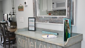 A kitchen with a rustic wooden cabinet displaying motivational phrases, a hanging light fixture, and a framed picture on the wall.