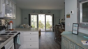Una cocina con una isla central, muebles blancos y un comedor con vistas al exterior.