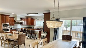 A spacious kitchen with wooden cabinets, a central island, and a dining area with a large wooden table and chairs. - Sand Castle, 9 bedroom,6 1/2 bath,sleep 26,  pool, hottub, elevator, beach close (Oak Island)
