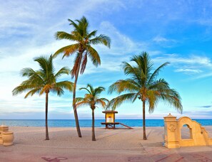 A beach with palm trees, a lifeguard tower, and a sea view. - Modern home away from home in a central location! (Hallandale Beach)