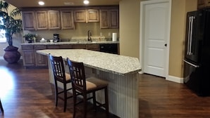 Una cocina con armarios de madera, encimera de granito, refrigerador y una planta en maceta.