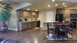 Una cocina amplia con armarios de madera, un comedor con mesa y sillas, y una planta grande en maceta.