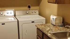 Una cocina con armarios de madera, encimera de granito, pileta de acero inoxidable y dos electrodomésticos blancos.