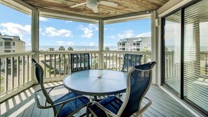 A covered outdoor area with a table and chairs, a ceiling fan, and a view of the ocean and neighboring houses. - Award-Winning Resort Amenities | Tidewater H304 (Isle of Palms)