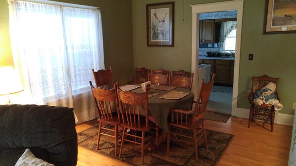 A dining area with a round table, six wooden chairs, and a patterned rug.