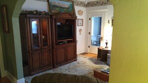 A living room with a wooden entertainment center, a television, and a patterned rug.