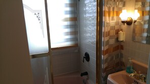Een bad/douchecombinatie, handdoeken, zeep, toiletpapier