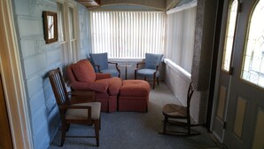 A room with a sectional sofa, two armchairs, a small table, and a rocking chair.