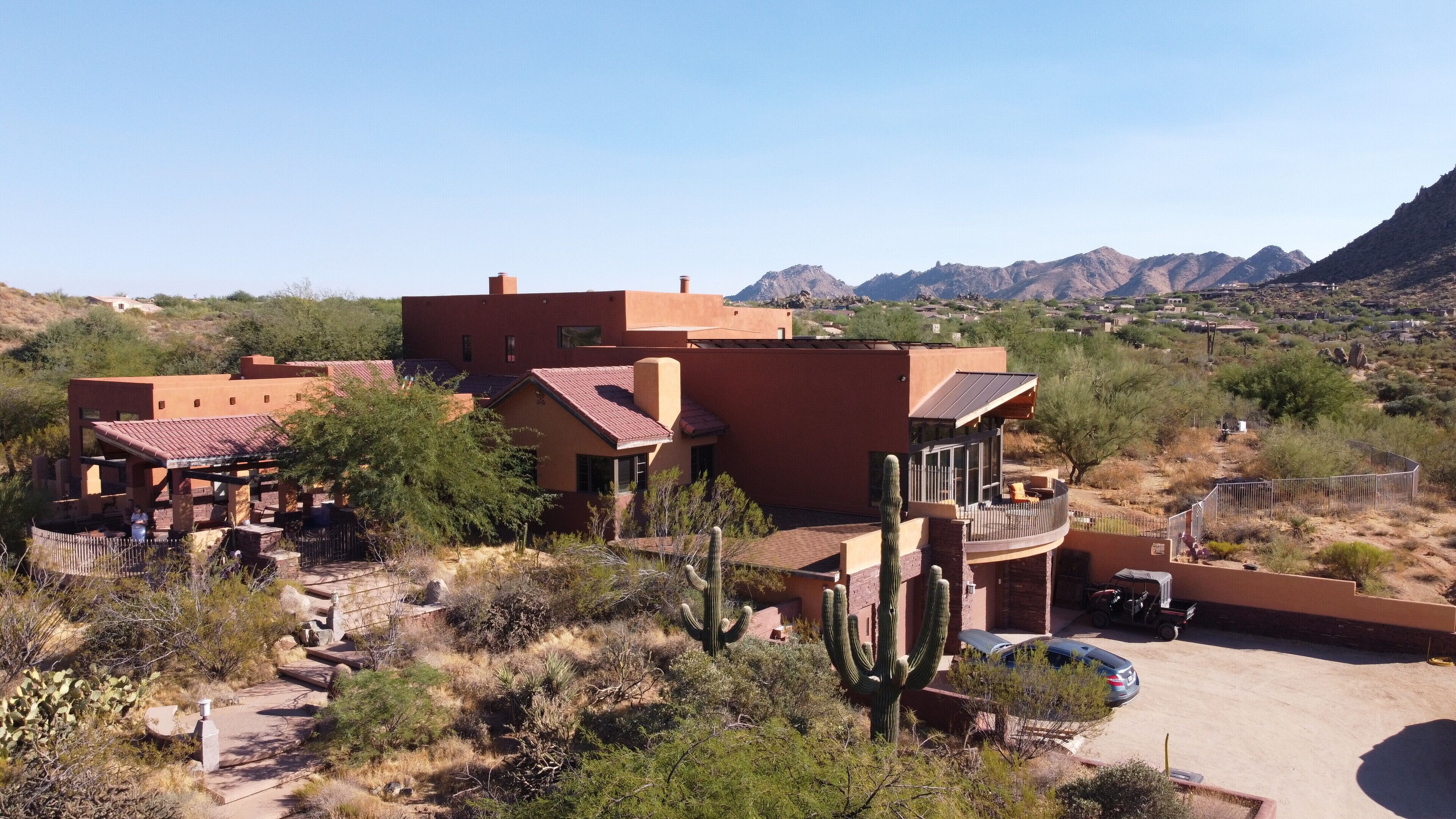 A desert-style building with multiple rooms and a patio area, surrounded by cacti and mountains in the background.