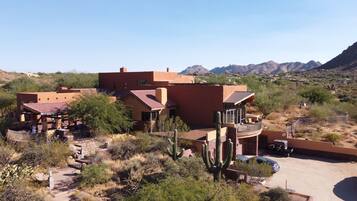A desert-style building with multiple rooms and a patio area, surrounded by cacti and mountains in the background.