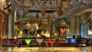 A bar area with a marble countertop, two martini glasses, and a variety of wall-mounted animal horns.